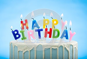 Blue Birthday Cake with Happy Birthday candles on Top on a Blue Background