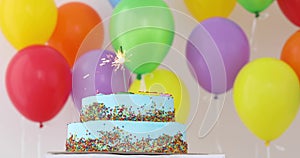 Blue Birthday cake with sparkler and colorful balloons