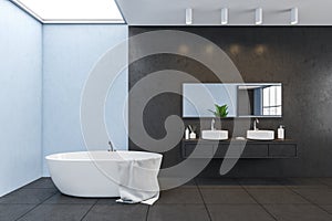 Blue and black walls in bathroom with bathtub and two sinks with mirror