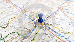 A blue board pin stuck in Bologna on a map of Italy photo