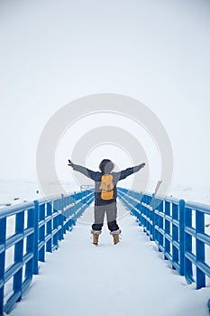 Blue boardwalk with woman arms outstretched on snowy day