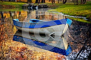 Blue boat on the lake in autumn forest.