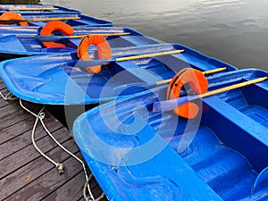 Blue boats with oars and orange lifebuoys