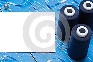 Blue bobbin thread and paper sheet on table. Copy space
