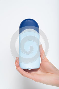 Blue bottle for cosmetic product in a female hand. White background