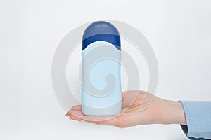 Blue bottle for cosmetic product in a female hand. White background