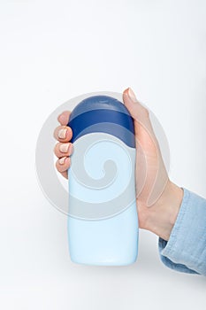 Blue bottle for cosmetic product in a female hand. White background