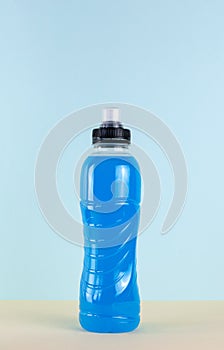 Blue bottle of isotonic drink, L-carnitine, sports energy drink on a blue background. Bottle of fitness drink.
