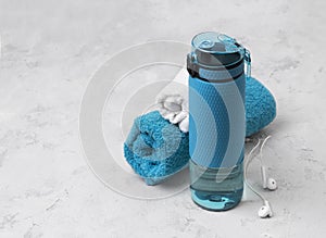 Blue bottle of water and towels. Sports equipment on gray concrete background