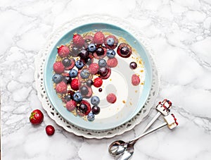 Blue bowl of hot oatmeal breakfast cereal with fresh berries, strawberries, cherries and blueberries from above