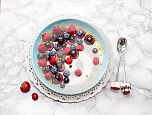 Blue bowl of hot oatmeal breakfast cereal with fresh berries, strawberries, cherries and blueberries from above