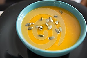 Blue bowl with pumpkin soup seasoned with seeds