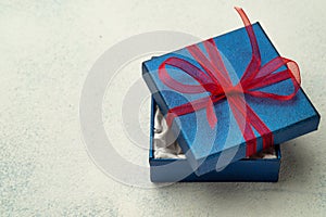 Blue box with a gift and a red ribbon on a light background with place for text