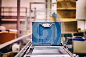 Blue boxes in a large, fully automated logistics warehouse run on a conveyor belt. Background is blurred. It is a modern storage