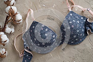 Blue bra on a concrete background. Delicate cotton and white feathers