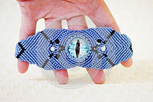 Blue bracelete with white beads and the dragon`s eye on the hand from waxed thread in the technique of macrame. Handmade photo