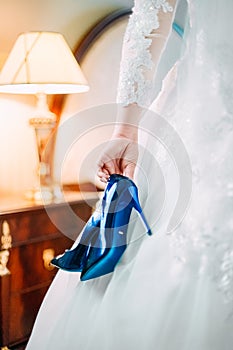 Blue bride`s wedding shoes is holding in her hand photo