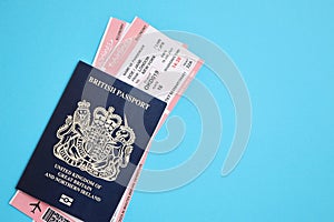Blue British passport with airline tickets on blue background close up