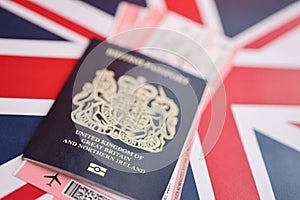 Blue British passport with airline tickets on national flag background close up