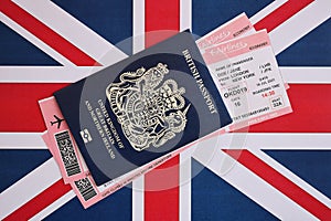 Blue British passport with airline tickets on national flag background close up