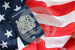 Blue British passport on United States national flag background close up