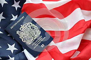 Blue British passport on United States national flag background close up