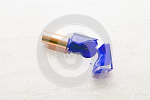 blue broken nail polish bottle or flask on white marble background, dye color splash and suffusion photo