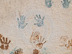 Blue and brown paint palm prints on the textured plaster