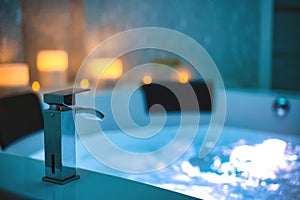 Blue bubbling Water in Spa Jacuzzi close-up faucet decorated with candles on the background, Relax and Lifestyle