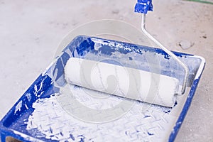 Blue bucket with paint and a brush roller paint tray