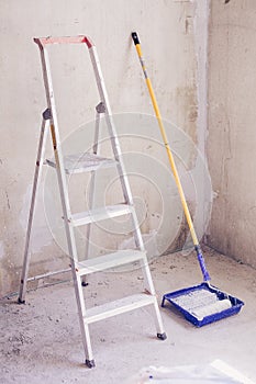 Blue bucket with paint, brush roller paint tray and ladder