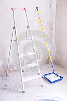 Blue bucket with paint, brush roller paint tray and ladder