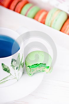 Blue butterfly pea flower tea and bitten green macaroon or macaron on the macarons background