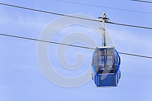 Blue cable car with passengers on a blue sky background.