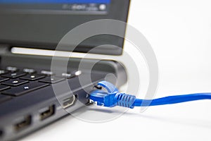 Blue cable network connection to a Lan port of laptop computer on white table