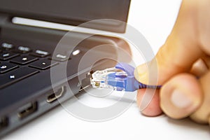 Blue cable network connection to a Lan port of laptop computer on white table