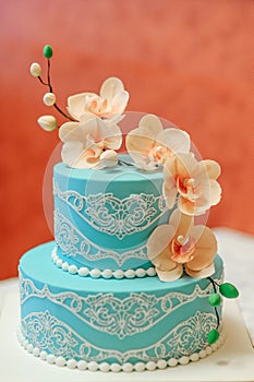Blue cake with a branch of orchids on a teracotta background