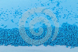 Blue cake topping sprinkles and sugar crystals on blue background - Abstract sprinkle background with copy space