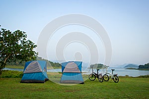 Blue camping tents and 2 bicycle on a shore in a morning