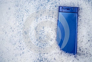 A blue can of shampoo floats in foamy water. The concept of cleanliness and personal care