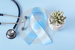 Blue cancer awareness ribbon with stethoscope on light background