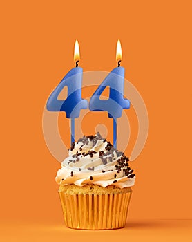 Blue candle number 44 - Birthday cupcake on orange background