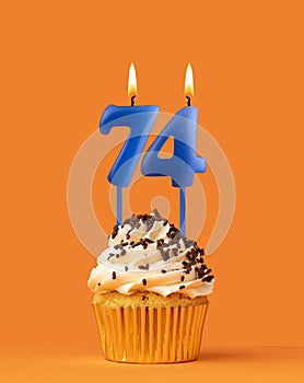 Blue candle number 74 - Birthday cupcake on orange background