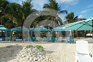 Blue canopy or beach tent on the white sand with palm trees behind in Nassau.