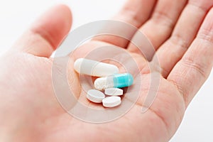 Blue capsule medicines and tablets in male hand.