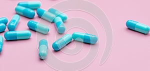 Blue capsule pills on pink background. Pharmaceutical industry. Capsule pill administration. Non drug therapy topics. Health