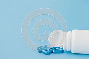 Blue capsules, pills on a blue background. Capsules in a white jar. Vitamins, nutritional supplements for women`s health