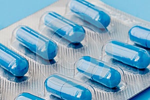 Blue capsules, pills on a blue background. Vitamins, nutritional supplements for women`s health