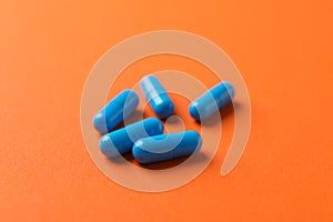 Blue capsules pills on orange background