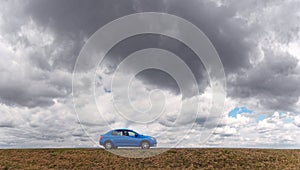 Blue car on a background of sky with clouds